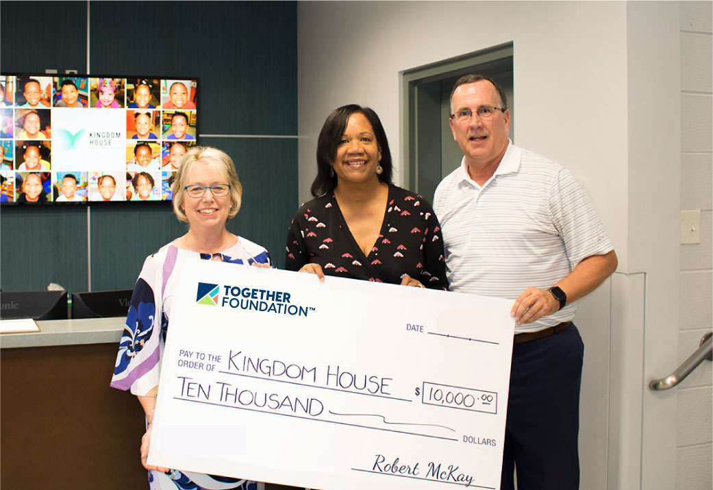 Chief Community Engagement Officer, Pier Alsup, presents a check for $10,000 to the Kingdom House